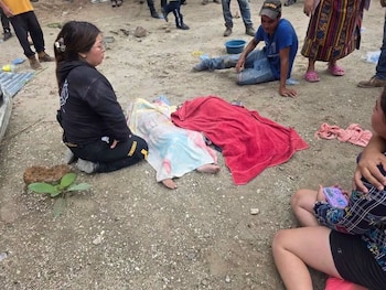 Casa de bloques frente a una ladera de tierra erosionada, con personas y maquinaria en los alrededores