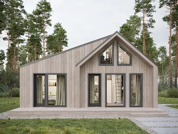Casa modular de madera clara con techo inclinado y grandes ventanales. Rodeada de césped, un camino de piedra y pinos altos bajo un cielo nublado