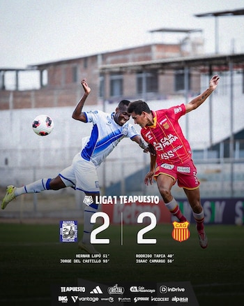 Dos futbolistas en acción, uno con camiseta blanca y azul, otro con camiseta roja y amarilla, saltan para cabecear el balón en un partido de fútbol. El marcador muestra un 2-2