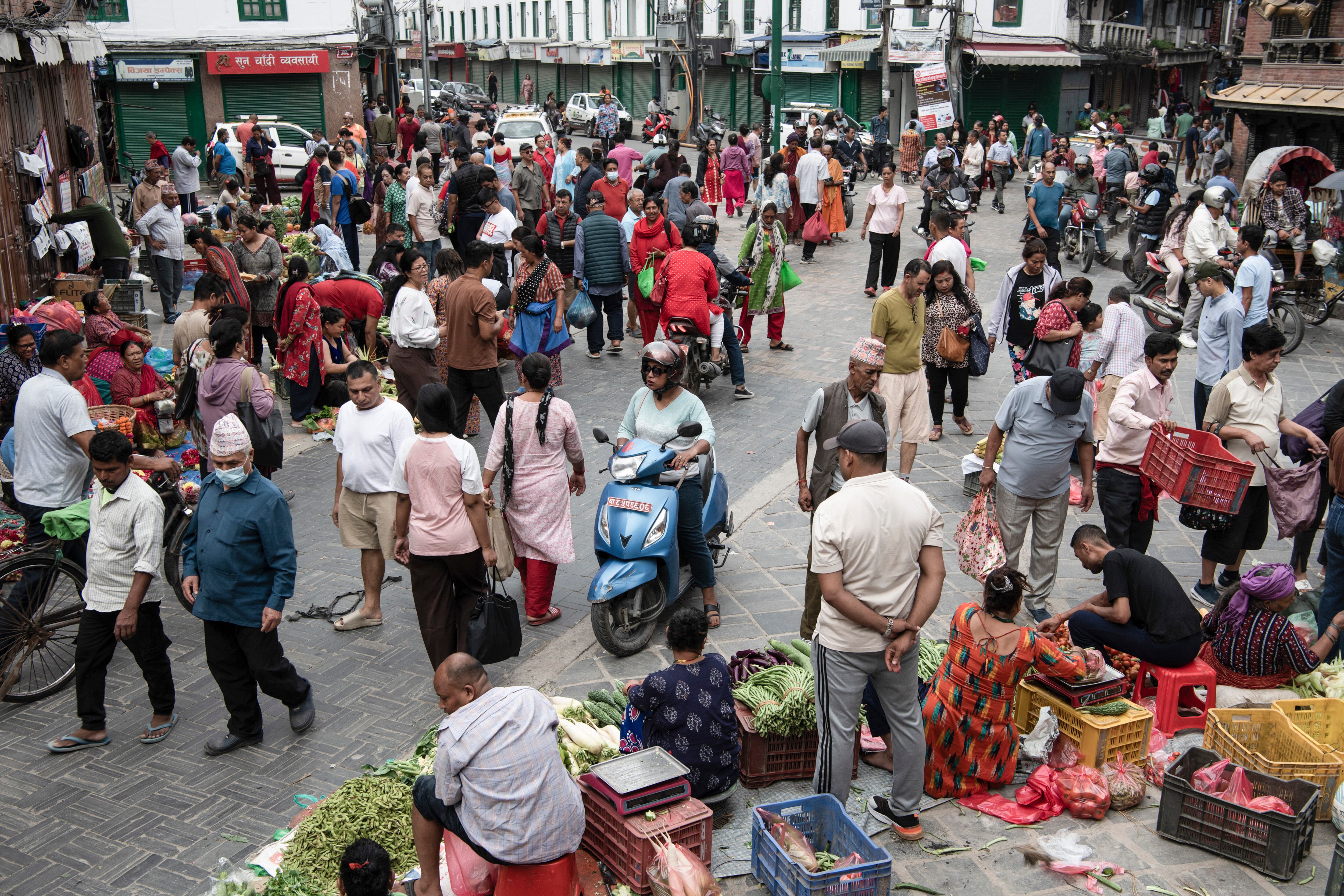Motorcycles, cars, and pedestrians at a vegetable market on a street in Kathmandu, Nepal, July 19, 2025. The narrow streets of Kathmandu are sized for pedestrians and rickshaws. (Rebecca Conway/The New York Times)