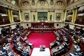 Vista panorámica del hemiciclo del Congreso de Perú con legisladores sentados en sus escaños y una bandera nacional al fondo