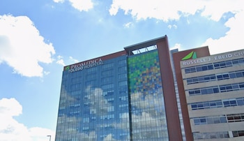Fachada acristalada de un edificio con el letrero de ProMedica Toledo Hospital bajo un cielo con nubes