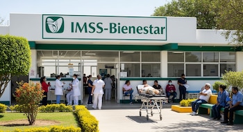Exterior de un hospital IMSS-Bienestar con su letrero verde, mostrando pacientes en una camilla y sentados, junto a personal médico en la entrada y áreas verdes.