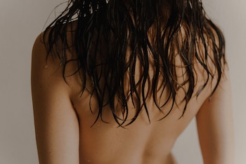 Una mujer de espaldas con el pelo mojado tras ducharse (Pexels)