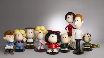 Colección de diez figuras de personajes de Mafalda: Mafalda, sus amigos, sus padres y la tortuga Burocracia. Se observan un libro, regadera, tijeras y chupete