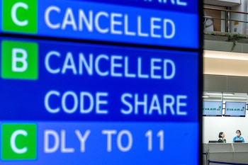 Una pantalla muestra vuelos cancelados mientras los empleados esperan en un mostrador de facturación en el aeropuerto de Naha, en la prefectura de Okinawa (Philip FONG / AFP)