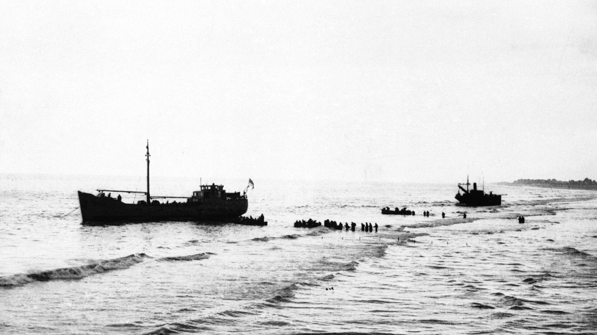 Soldados forman fila en el agua para subir a las embarcaciones y abandonar Francia (AP Photo)