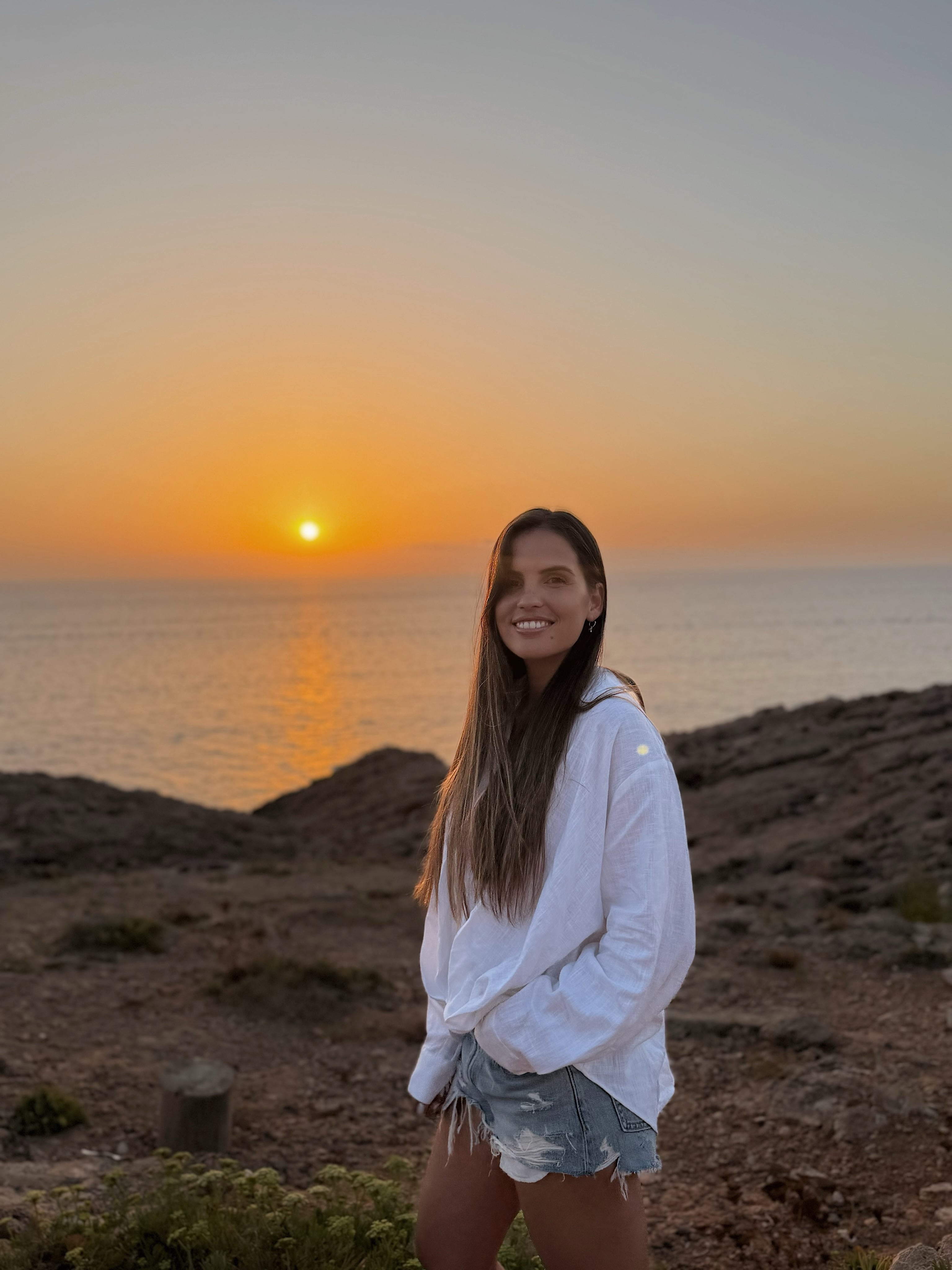 Emilia Ferrero posa sonriente frente al mar durante un atardecer en Ibiza, en el marco de sus vacaciones.