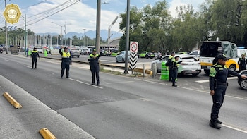 Cuatro oficiales de policía dirigen el tráfico en una calle concurrida frente al Estadio Olímpico Universitario, con varios vehículos policiales y coches civiles