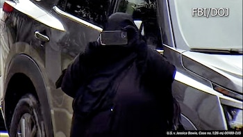 Persona vestida de negro cubriendo su rostro con un teléfono móvil frente a un coche oscuro. Se observan los textos FBI/DOJ y U.S. v. Jessica Bowie