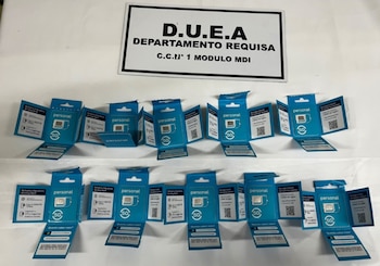 Diez envases abiertos de tarjetas SIM de color azul expuestos bajo un cartel informativo del Departamento Requisa