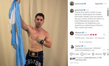 Gastón Edul, un hombre sin camiseta con pantalón corto y vendas de boxeo, sostiene una bandera argentina delante de una pared lisa. Se observa una interfaz de Instagram