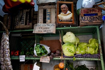 Una foto del papa Francisco colocada junto a un cartel que avisa del costo de pagar con tarjeta de débito o crédito en una verdulería porteña (AP Foto/Natacha Pisarenko, Archivo)