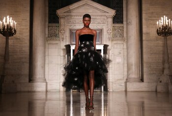 Tul y bordado. Con escote strapless, el diseño de couture by Oscar de la Renta en negro con bordado de destellos, y corte irregular en el largo de la falda para la propuesta del invierno 2020-2021