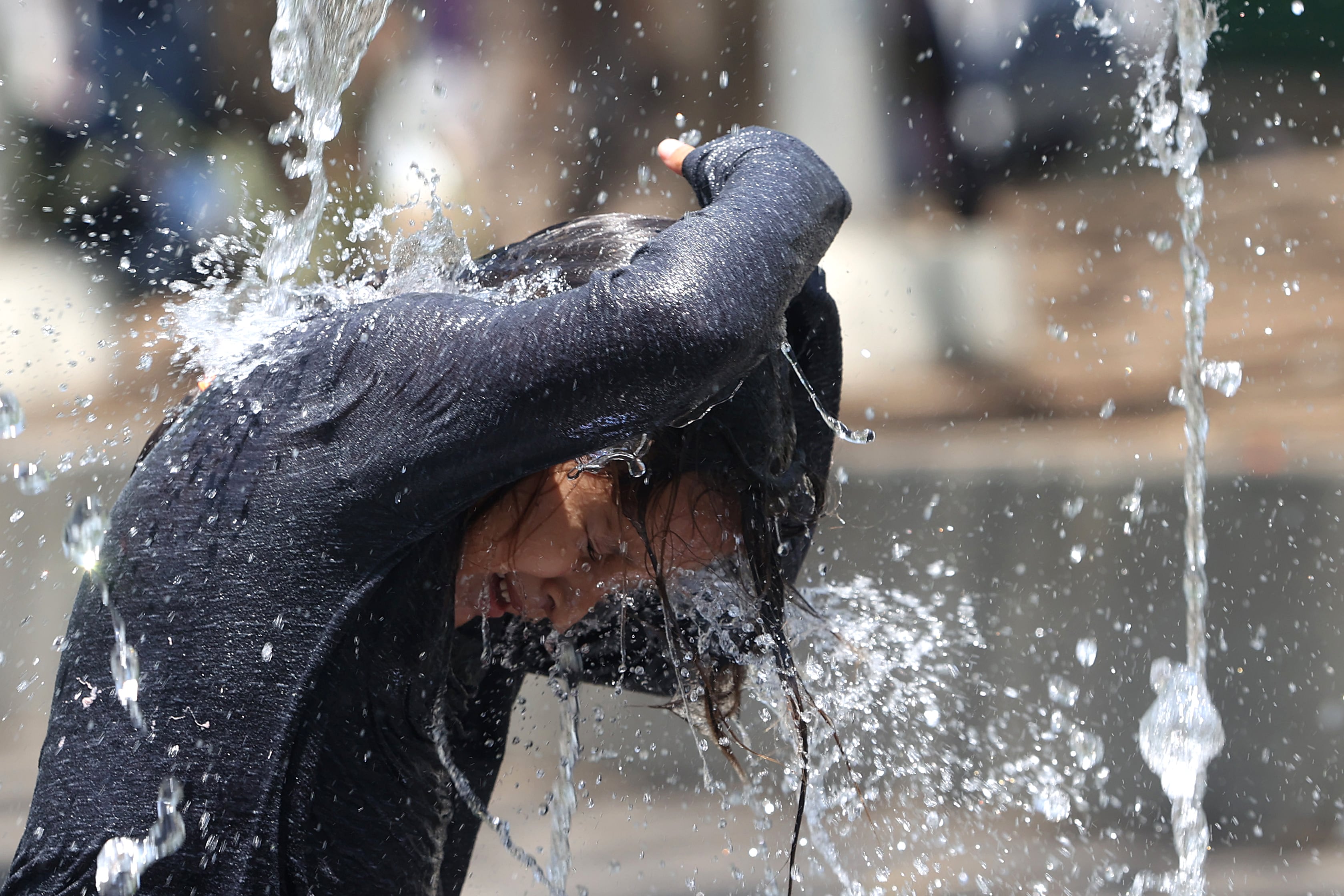 Un niño fue captado este 12 de mayo al refrescarse en una fuente, para enfrentar la ola de calor que genera