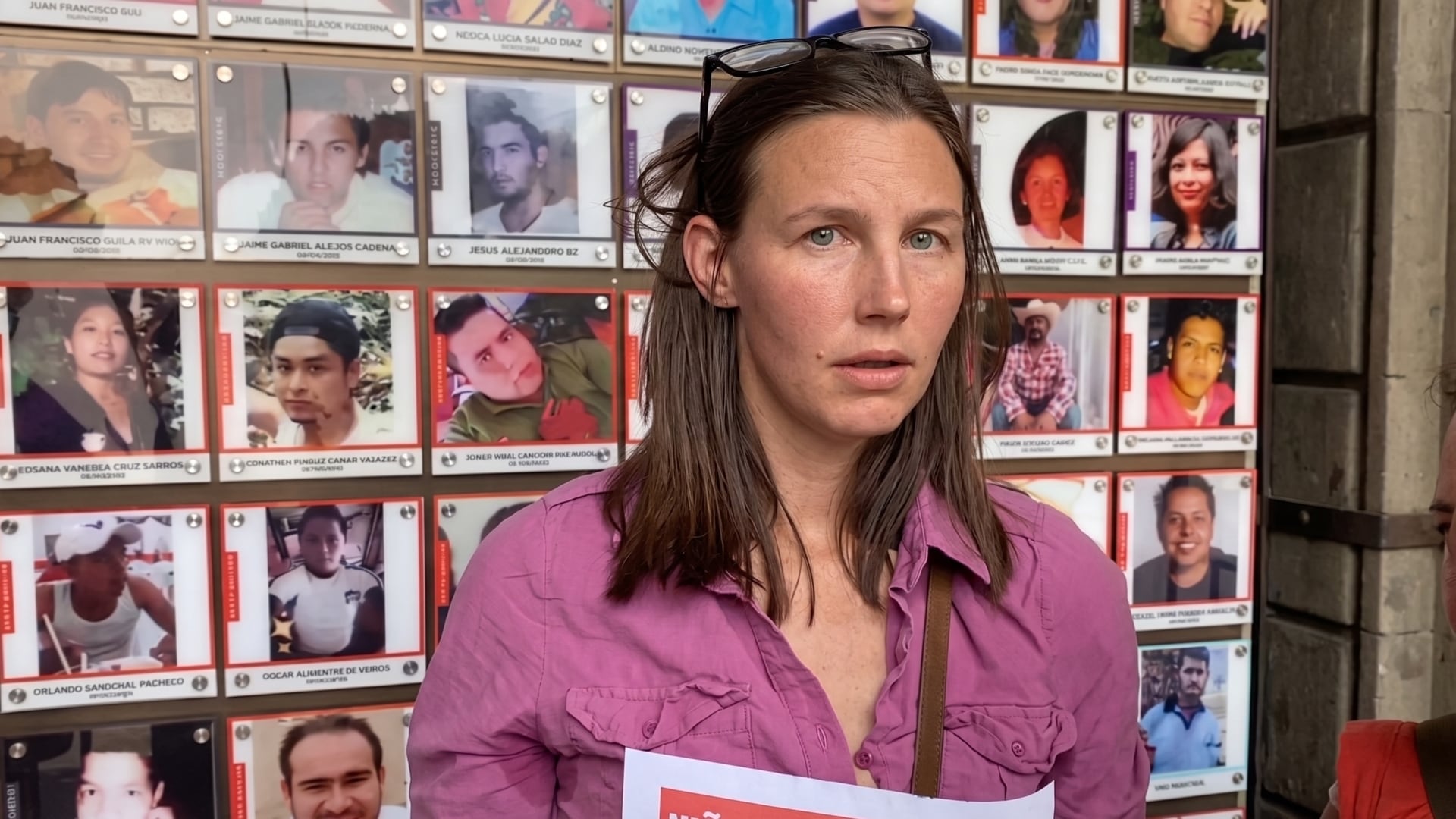 Maley Deh Lenschlager, ciudadana estadounidense, exige la localización de su hijo desaparecido en Tepoztlán, Morelos, frente a un muro de fotografías de personas extraviadas. (Captura de pantalla: X)