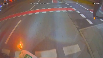 Calzada de asfalto de noche con marcas viales blancas y rojas, datos de velocidad en cero y parte de un manillar con luz naranja