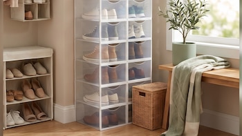 Cajas de plástico apiladas con zapatos, organizadores de tela, una canasta, una planta en maceta y un banco de madera junto a una ventana.