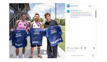 Lionel Messi, Rodrigo De Paul y Franco Colapinto posan al aire libre, sonriendo y sosteniendo tres camisetas azules con la frase 'Argentina Llena de Energía' y sus apellidos