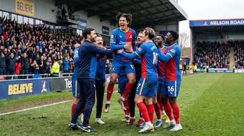 Jugadores del AFC Richmond, con Dani Rojas en el aire, celebran un gol en un campo de fútbol embarrado. El entrenador Ted Lasso está entre ellos, con fans en las gradas.