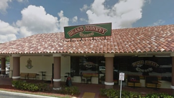 Fachada de un edificio con un cartel que dice 'Brass Monkey Tavern', techo de tejas rojas y blancas, columnas marrones y ventanas oscuras