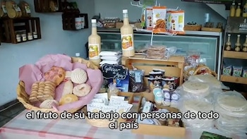Una canasta con pan dulce variado, dos botellas de bebida cremosa, un cartel de galletas de maíz, bolsas de snacks y pilas de tortillas