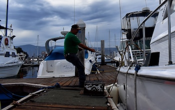 Un hombre asegura las embarcaciones de la bahía de Ensenada, en el estado de Baja California (México). EFE/Archivo