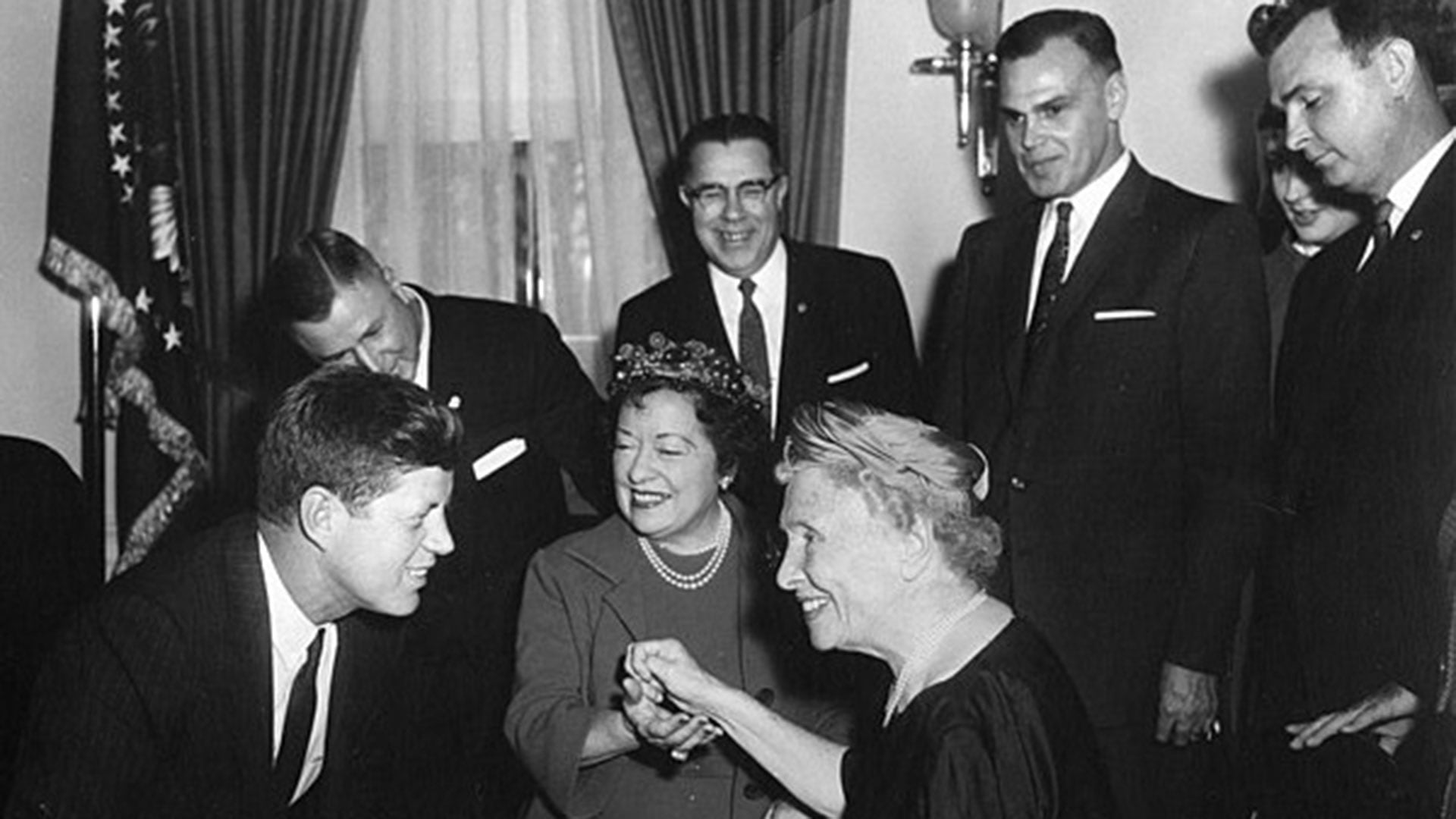 El presidente John F. Kennedy recibe a Helen Keller en el Despacho Oval de la Casa Blanca el 8 de abril de 1961. En el centro, su secretaria personal, Evelyn Seide, le transmite mediante pulsaciones táctiles el mensaje del mandatario (fundacionhelenadamskeller.com)