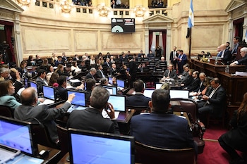 Vista elevada de un recinto legislativo semicircular con personas sentadas en bancas frente a computadoras y pantallas electrónicas