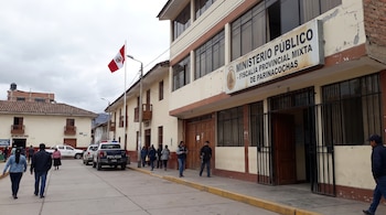 Edificio de la Fiscalía Provincial Mixta de Parinacochas, bandera de Perú, personas y vehículos policiales en la calle, señal de Ayacucho.