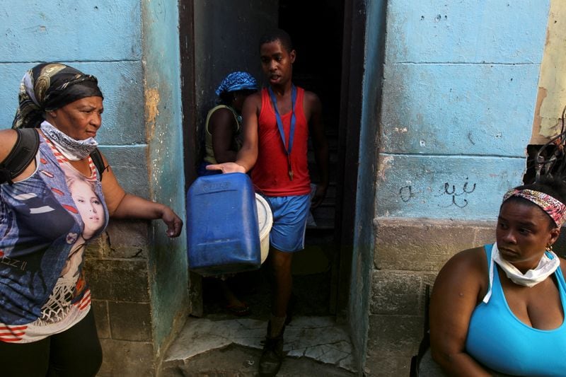 Yosniel Iznaga lleva contenedores para recolectar agua de un camión en La Habana, Cuba (REUTERS/Stringer/Archivo)