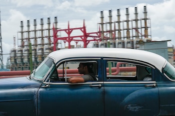 Una persona conduce un automóvil clásico estadounidense junto a un generador flotante que no produce electricidad desde hace días en La Habana, Cuba, el viernes 18 de octubre de 2024 (AP Foto/Ramón Espinosa)