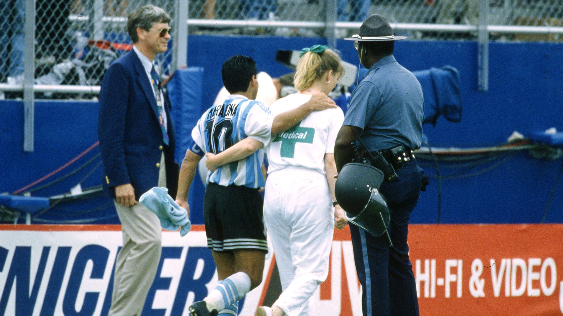 Maradona sale de la cancha tras el triunfo contra Nigeria junto a la asistente que lo llevó hasta el control antidoping (Grosby)