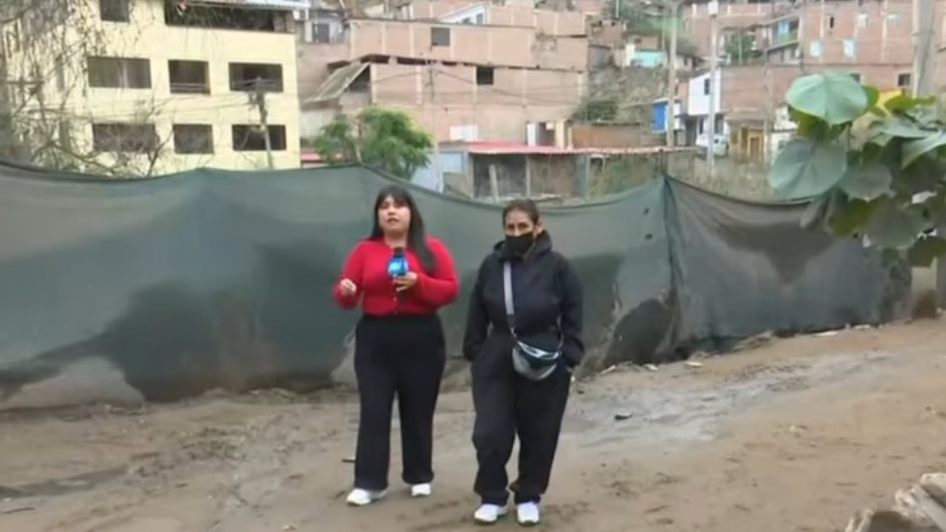 Una reportera y una vecina recorren una calle embarrada en José Gálvez, Villa María del Triunfo, tras las intensas lluvias registradas en la zona. (Captura: ATV Noticias)