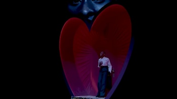 Cynthia Erivo está de pie dentro de una estructura roja brillante con forma de corazón. Detrás, una silueta de un rostro en tonos azules oscuros mira hacia abajo