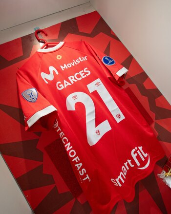 Camiseta roja de fútbol colgada en un perchero, con el apellido Garcés y el número 21 impresos en letras y números blancos en la espalda