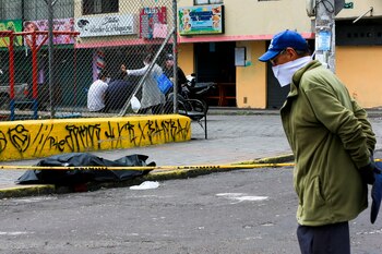 Policía con trajes especiales y personal sanitario asisten a una persona que yace en el piso, tras desplomarse y donde criminalística de la policía realizó las pruebas de COVID-19 y determinó que falleció por otras causas (EFE)