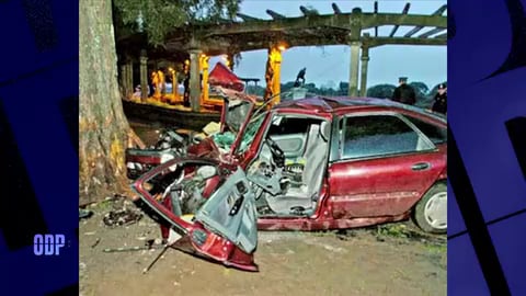Un automóvil rojo destruido se encuentra junto a un árbol tras el accidente sufrido por el exboxeador Jorge Roña Castro.