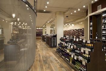 Estantes de madera con botellas de vino alineadas, piso de tablas de madera, lámparas colgantes y una cortina metálica divisoria
