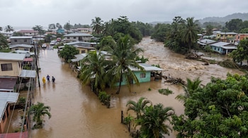 Vista aérea de una zona residencial en Limón, Costa Rica, con calles y casas inundadas por agua lodosa. Un río desbordado atraviesa el paisaje.