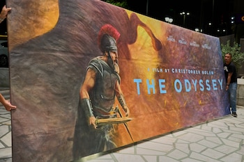 Trabajadores instalan un cartel pintado a mano, obra de la artista Virginia Axioti, para la próxima película de Christopher Nolan, "The Odyssey", protagonizada por Matt Damon en el papel de Odiseo, frente al cine Athinaion de Atenas, el sábado 11 de julio de 2026. (Foto AP/Petros Giannakouris)