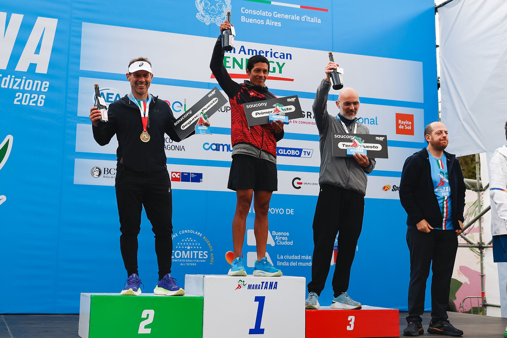 Los ganadores de MaraTANA 2026 celebran en el podio, alzando sus botellas de premio y mostrando sus medallas con orgullo tras la exitosa competición en Buenos Aires.
