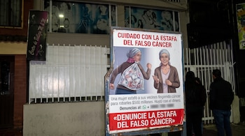 Cartel en la calle con ilustraciones y un texto impreso sobre la estafa del falso cáncer y un número para denuncias.