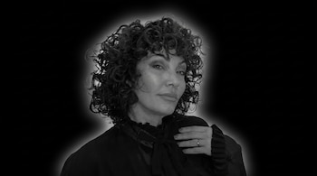 Retrato de Ernestina Pais, una mujer de cabello rizado en blanco y negro sobre fondo oscuro. Viste blusa con lazo y lleva un anillo.
