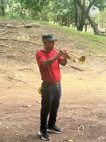 El ruido de los trabajos finales a varias de las obras que acogerán los Juegos Centroamericanos y del Caribe de Santo Domingo 2026, a inaugurarse el viernes próximo, no impide a Frank Casado ejecutar las notas de su trompeta bajo el cobijo de un almendro en el Centro Olímpico Juan Pablo Duarte, principal escenario del evento. EFE/ Ramón Santos Lantigua