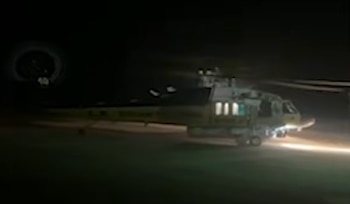 Helicóptero en un terreno oscuro iluminado por sus propios faros durante la noche