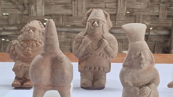 Varias estatuillas de cerámica modelada con figuras humanas y ornitomorfas se encuentran sobre una mesa con fondo de petate
