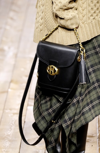 Maxi tejidos como polerones y faldas en tartan en verde inglés para complementar los bolsos de la nueva colección de Michael Kors. En pasarela, un modelo en negro con cadena dorada con el tradicional logotipo de la firma