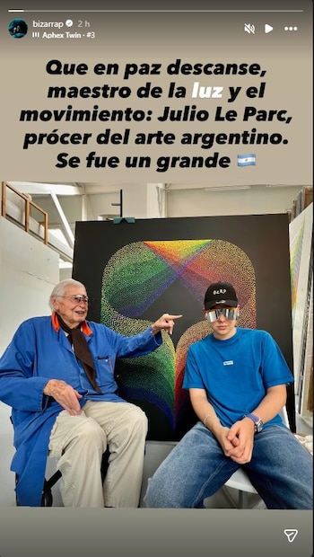 El productor Bizarrap y Julio Le Parc, el artista óptico argentino, sentados frente a una obra abstracta de colores vibrantes