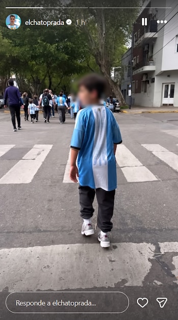 Vista trasera de un niño con el rostro borroso y la camiseta de Argentina cruzando un paso de peatones junto a otras personas.